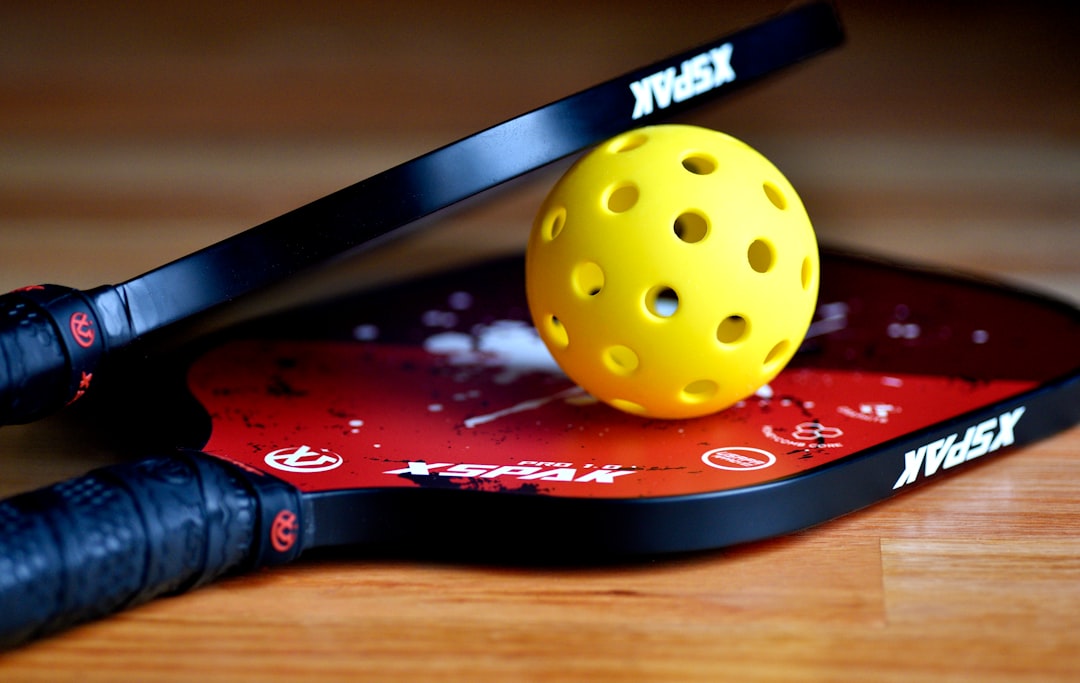 a yellow tennis ball sitting on top of a racket
