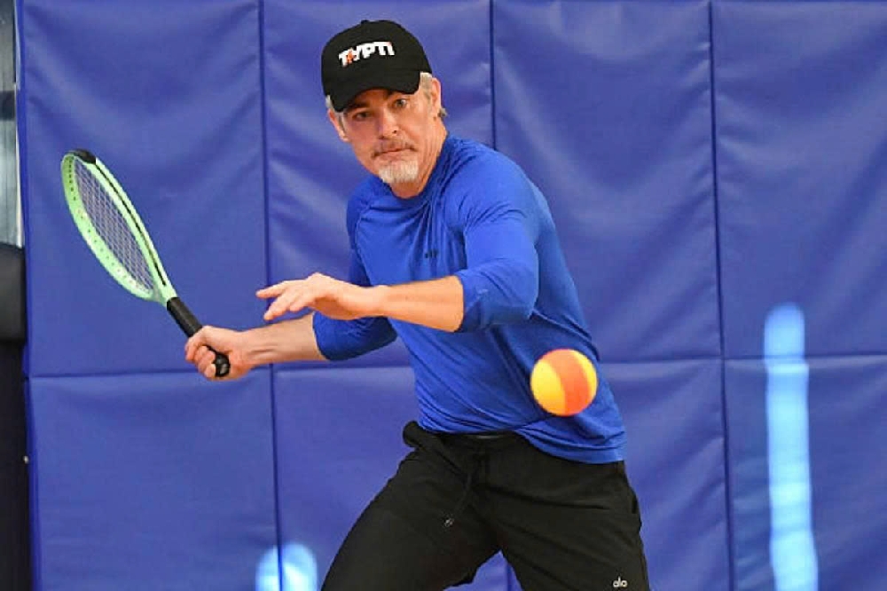 Người chơi Typti smash mạnh với vợt lưới trên sân tiêu chuẩn